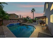 Inviting backyard oasis featuring a sparkling pool, covered patio, and lush landscaping at 3448 W Sunshine Butte Dr, San Tan Valley, AZ 85144