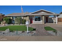 Ranch-style home with landscaped lawn, red door, and brick facade at 6334 W Vogel Ave, Glendale, AZ 85302