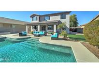 Inviting backyard oasis featuring a sparkling pool, patio furniture, and lush landscaping at 14877 N 145Th Dr, Surprise, AZ 85379