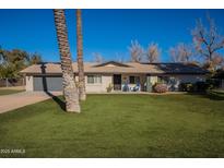 Charming single-story home with a well-manicured lawn, lush landscaping, and a cozy porch with blue chairs at 616 E Country S Plz, Gilbert, AZ 85234