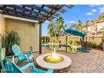 Relaxing backyard oasis with a fire pit, pool, pergola, and lounge chairs for outdoor enjoyment at 18456 E Superstition Dr, Queen Creek, AZ 85142