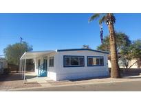 White single-wide mobile home with blue trim, covered carport, and desert landscaping at 201 S Greenfield Rd # 16, Mesa, AZ 85206