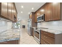 Modern kitchen with stainless steel appliances, granite countertops and wood cabinets overlooking a living room with a fireplace at 5998 N 78Th St # 116, Scottsdale, AZ 85250