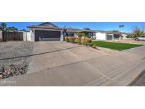 House exterior featuring artificial turf, landscaping, and a large driveway at 13418 N 50Th St, Scottsdale, AZ 85254