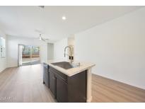 Bright kitchen features a center island with sink, laminate flooring, and an open floor plan at 2557 W Gaby Rd, Phoenix, AZ 85041