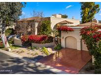 Spanish style home with red flowers, two car garage, and a large driveway at 7500 E Mccormick Pkwy # 11, Scottsdale, AZ 85258