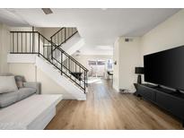 Open living area with staircase, hardwood floors, and large TV at 8375 E Indian School Rd, Scottsdale, AZ 85251