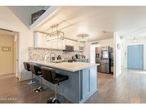 Modern kitchen with blue cabinets, quartz countertops, stainless steel appliances, and breakfast bar at 6352 W Campo Bello Dr, Glendale, AZ 85308