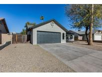 Ranch style home with gray garage door and landscaped yard at 6934 W Mclellan Rd, Glendale, AZ 85303