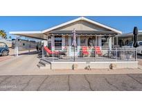 Tan mobile home with covered porch, red chairs, and landscaped yard at 8865 E Baseline Rd # 1106, Mesa, AZ 85209