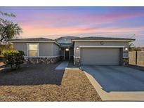 Single-story home with a gray exterior, two-car garage, and desert landscaping at 18439 W Wind Song Ave, Goodyear, AZ 85338