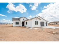Inviting white stucco home featuring a three-car garage and desert landscape at 25505 W Brookhart Way, Wittmann, AZ 85361