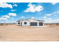 Charming white stucco home featuring a three-car garage and desert landscape at 25505 W Brookhart Way, Wittmann, AZ 85361