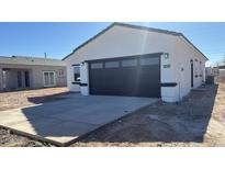 New construction home boasts a black paneled garage door, clean white stucco exterior, and an ample concrete driveway at 3215 W Sueno Dr, Eloy, AZ 85131