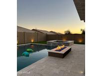 Backyard pool and spa featuring a fire pit, creating a serene outdoor oasis with privacy fencing and landscape lighting at 12075 E Chevelon Trl, Gold Canyon, AZ 85118