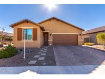 One-story house with tan exterior, brown garage door, and landscaped front yard at 17215 W Molly Ln, Surprise, AZ 85387