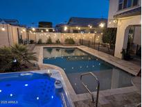 Backyard pool with an attached jacuzzi surrounded by charming string lights at night at 20552 W Carlton Mnr, Buckeye, AZ 85396