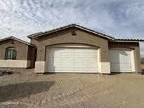 Exterior view of the garage with white doors and tan stucco finish, complementing the home's architecture at 21916 W Duane Ln, Wittmann, AZ 85361