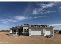 New construction home with a two-car garage under a blue sky ready for new roof tiles in a desert landscape at 29577 N 220Th Ave, Wittmann, AZ 85361