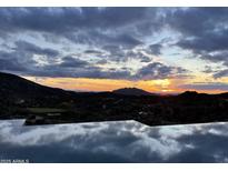 Stunning sunset over a golf course and mountain range, reflecting in a large pool at 41104 N 96Th St, Scottsdale, AZ 85262