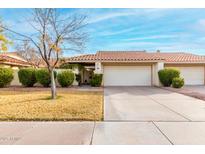 Tan stucco house with tile roof, two-car garage, and well-manicured lawn at 7373 S Bonarden Ln, Tempe, AZ 85283