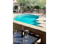 Relaxing patio with pool view, table, wine, and glasses at 29606 N Tatum Blvd # 216, Cave Creek, AZ 85331