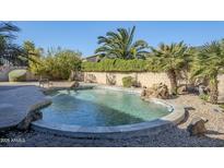 Relaxing kidney shaped pool with a waterfall feature in the backyard at 10406 E Laguna Azul Ave, Mesa, AZ 85209