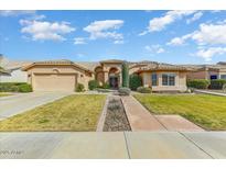 Single-story home with a landscaped yard, two-car garage, and inviting walkway at 18903 N 87Th Dr, Peoria, AZ 85382