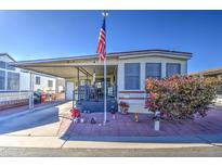 Mobile home with covered porch, landscaping, and American flag at 7750 E Broadway Rd # 156, Mesa, AZ 85208