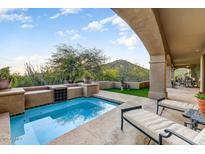 Relaxing backyard oasis featuring a sparkling pool, comfortable seating, and mountain views at 13462 E Wethersfield Rd, Scottsdale, AZ 85259