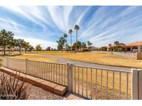 View of a lush green golf course from behind a white fence at 25432 S Queen Palm Dr, Sun Lakes, AZ 85248