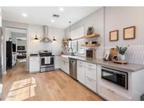 Modern kitchen featuring white cabinets, stainless steel appliances, and light wood flooring at 42949 N Voyage Trl, Phoenix, AZ 85086