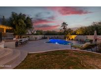 Inviting kidney-shaped pool with outdoor entertaining area at sunset at 7760 E Carefree Dr, Carefree, AZ 85377