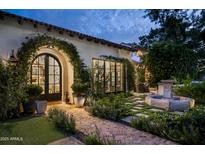 Elegant home exterior with arched entryway, lush landscaping, and stone pathway at 7305 E Royal Palm Rd, Scottsdale, AZ 85258