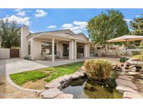 Serene backyard oasis with covered patio, pond, and waterfall at 3830 E Carter Dr, Phoenix, AZ 85042