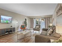 Bright living room with comfy seating, large TV, and sliding glass doors to patio at 7625 E Camelback Rd # B148, Scottsdale, AZ 85251
