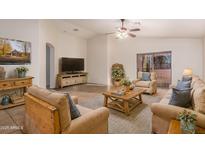 Bright living room features neutral furnishings, vaulted ceiling with ceiling fan, and sliding glass doors to patio at 14033 W Two Guns Trl, Surprise, AZ 85374