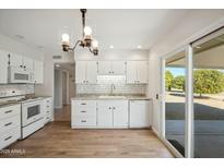 Modern kitchen with white cabinets and sliding glass door at 19619 N Signal Butte Cir, Sun City, AZ 85373