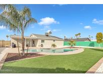 Inviting backyard oasis with sparkling pool, lush grass, and mature palm trees at 557 S Visalia St, Mesa, AZ 85202