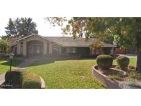 Single-story home with a large front yard, mature trees, and a brick walkway at 833 E San Angelo Ave, Gilbert, AZ 85234