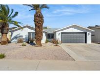 White brick house with gray garage door, landscaping, and palm trees at 4242 E Sacaton St, Phoenix, AZ 85044