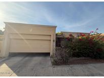 Tan house with two-car garage and red flowering bushes at 10846 N 11Th St, Phoenix, AZ 85020