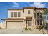 Two-story house with tan exterior, stone accents, and a three-car garage at 28396 N Tourmaline Dr, San Tan Valley, AZ 85143