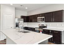 Spacious kitchen featuring dark cabinetry, quartz countertops, and stainless steel appliances at 11225 E Marigold Ln, Florence, AZ 85132