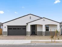 Charming single-story home featuring a gray two-car garage, quaint porch, and low maintenance landscaping at 17697 W Southgate Ave, Goodyear, AZ 85338