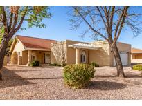 Tan one-story house with red tile roof, a pergola, and well-manicured landscaping at 25636 S Howard Dr, Sun Lakes, AZ 85248