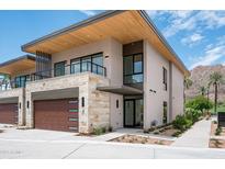 Beautiful modern home with a stone facade, wood garage door, and a second story balcony at 4575 N Phoenician Blvd # 2, Scottsdale, AZ 85251