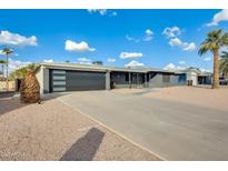 Ranch style home with gray exterior, modern garage door, and landscaped front yard at 6702 E Adobe St, Mesa, AZ 85205