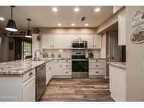Modern kitchen with granite countertops, white cabinets, and stainless steel appliances at 17826 N Buntline Dr, Sun City West, AZ 85375