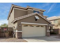 Two-story house with beige exterior, a large garage, and a well-maintained front yard at 224 S 151St Ave, Goodyear, AZ 85338